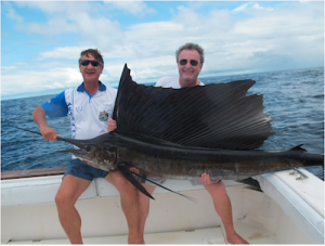 two middle aged men on boat holding a huge marlin